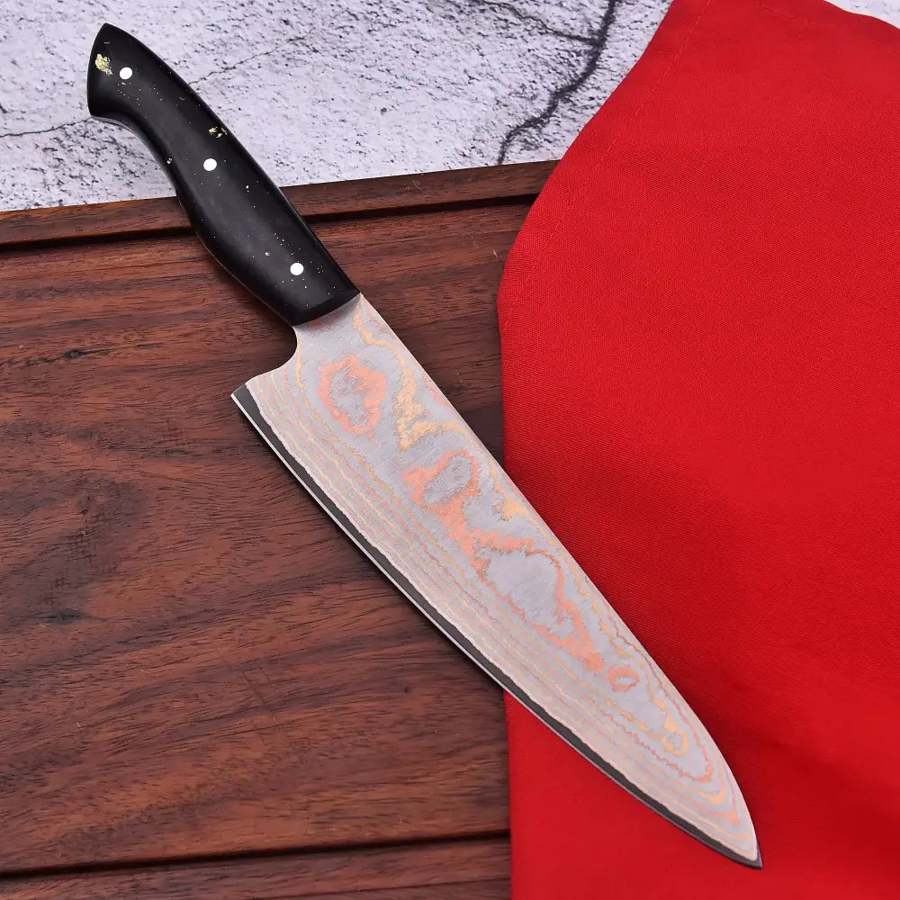 Damascus chef knife with black handle and swirling silver copper blade