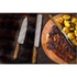 Pair of Damascus steel knives with wooden handles beside steak and potatoes