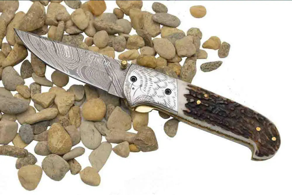 Faneema Cutlery Damascus pocket knife with patterned blade and textured handle on stones