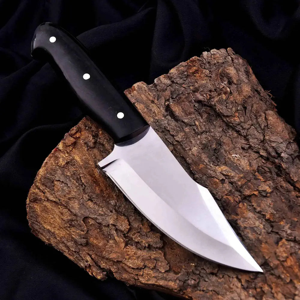 Black-handled sooty outdoor knife with polished stainless steel blade on tree bark