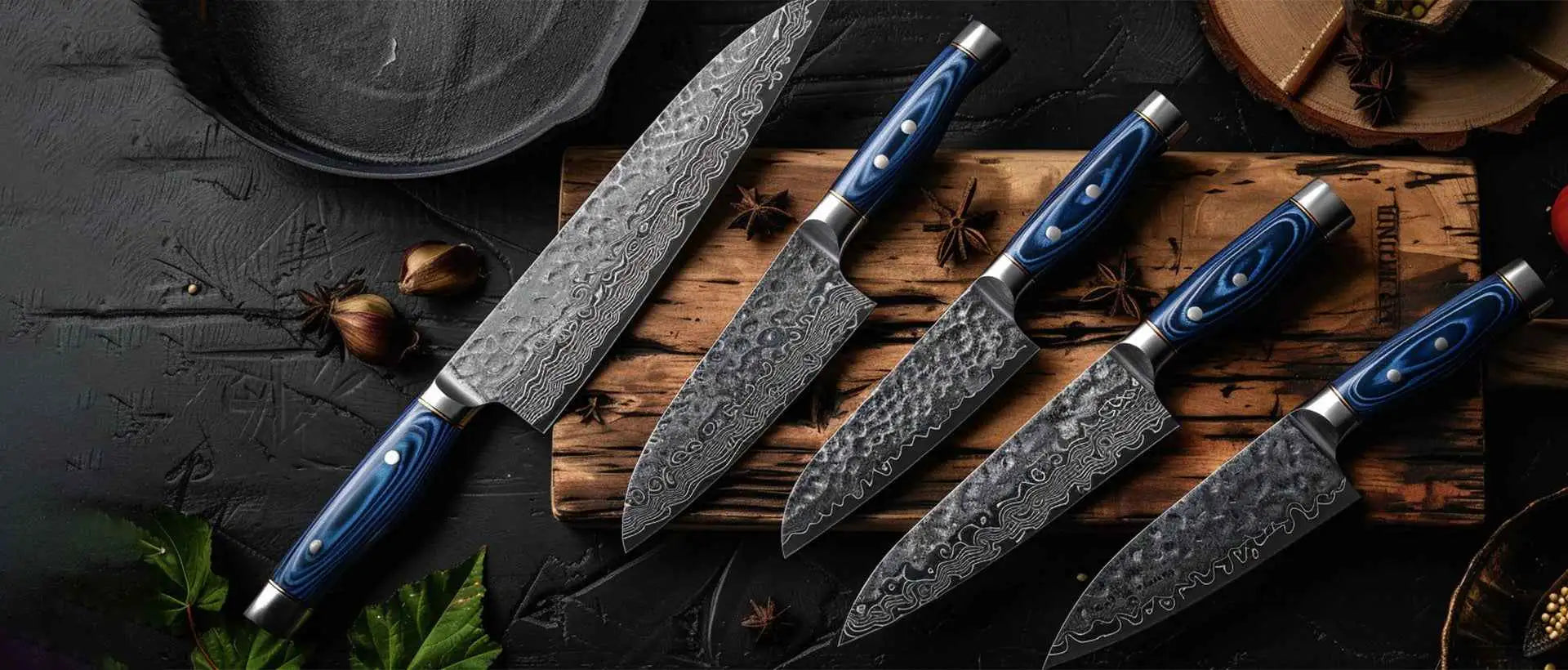 Set of four knives with blue handles and damascus steel blades arranged on a wooden cutting board.